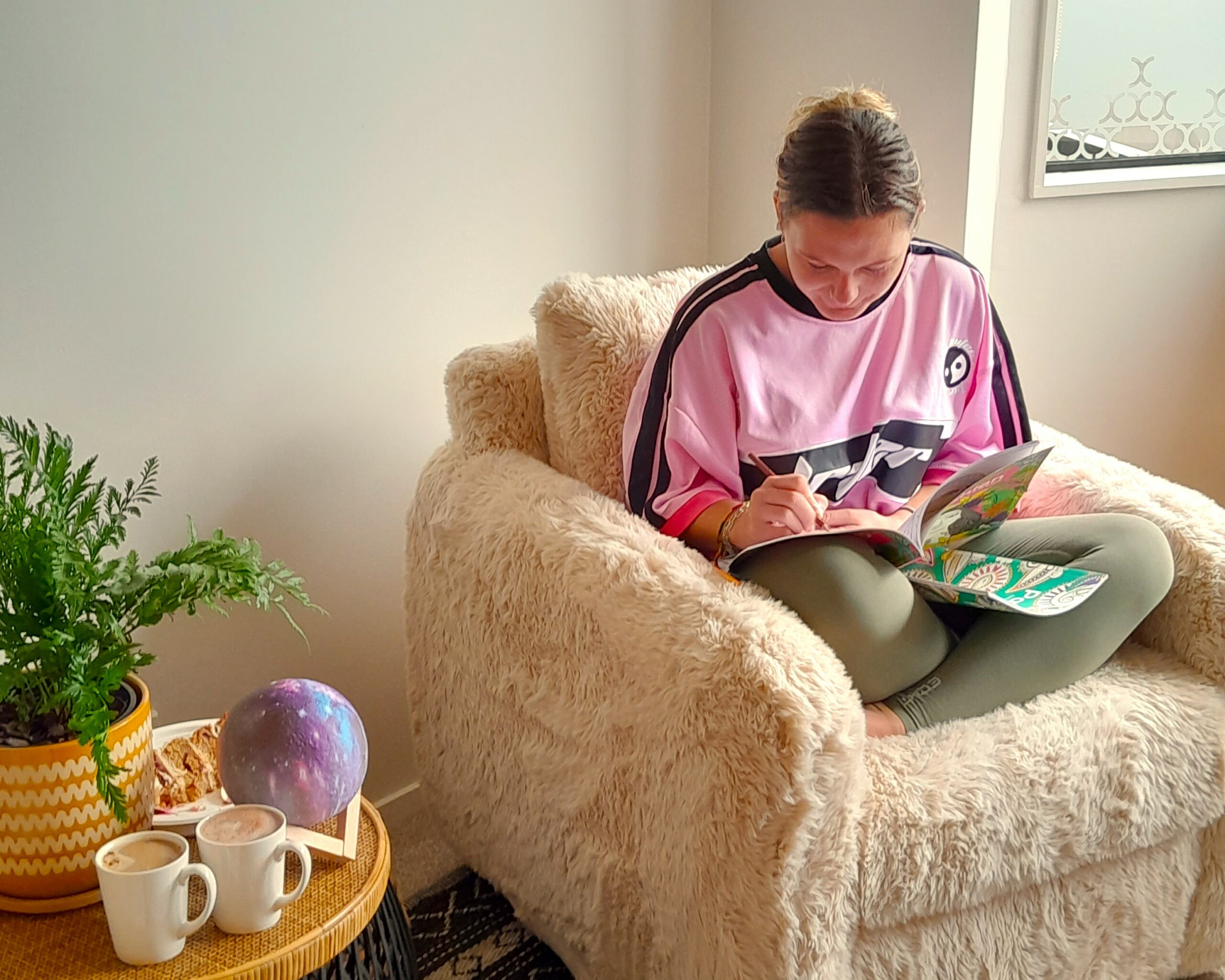 Taiohi sitting in a chair writing.